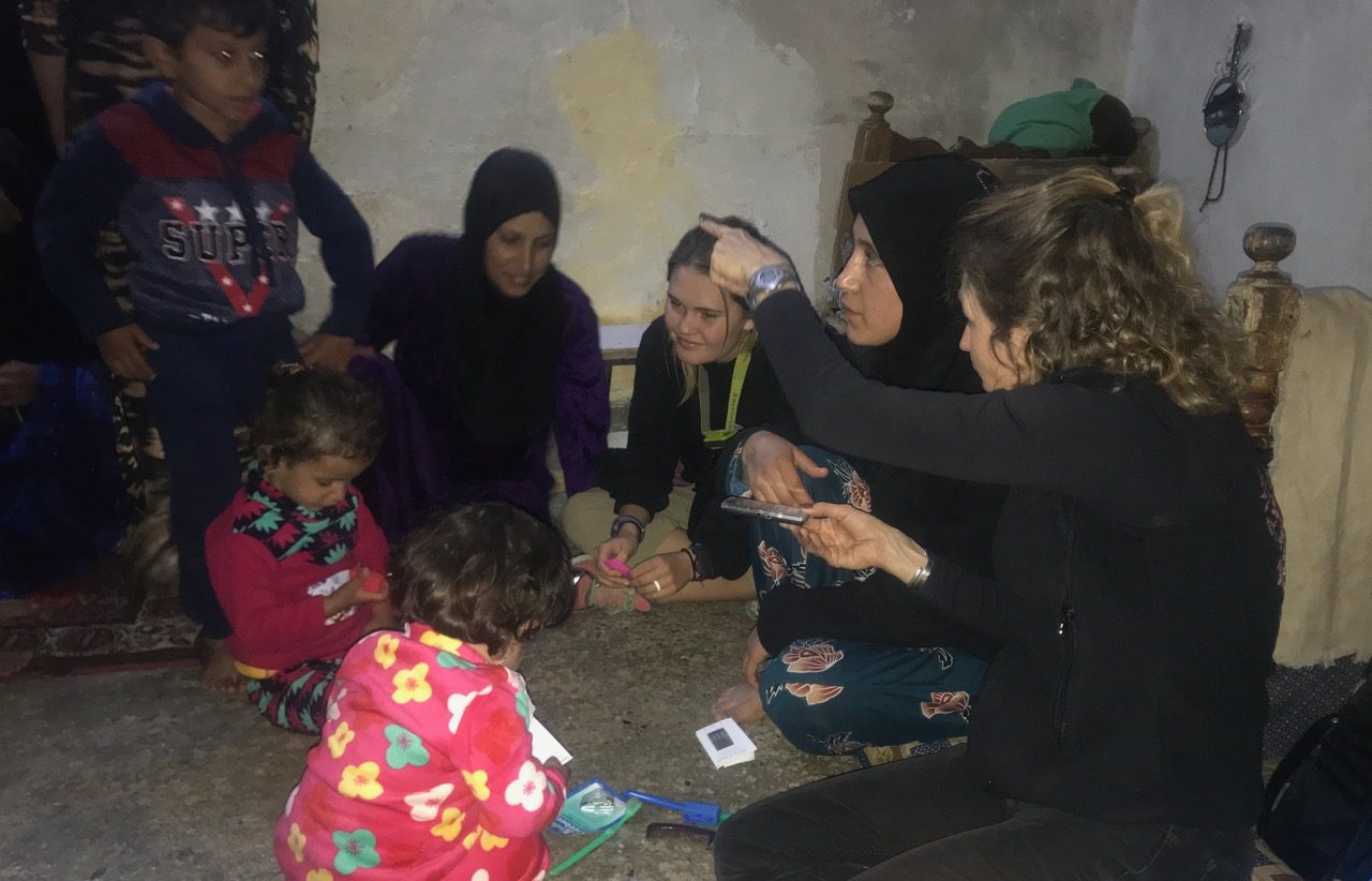 Women and children at home receiving audio Bible players